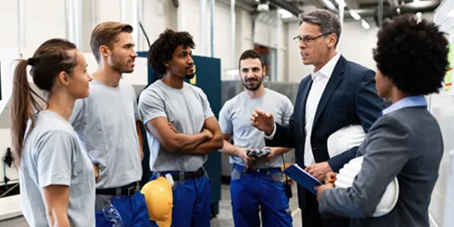 corporate-manager-talking-group-manual-workers-while-having-staff-meeting-factory Manpower Supply Recruitment - Service page - Page Insert